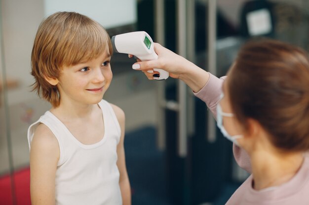 Medición de la temperatura infantil con termómetro láser en el jardín de infantes