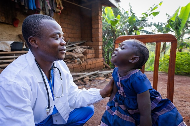 Médico africano hablando con una niña enferma durante una visita a una zona rural de África