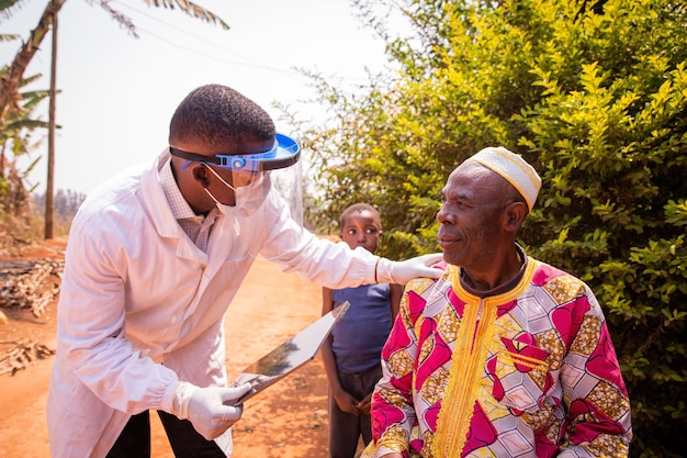 Foto médico africano visita a un paciente anciano y conversan durante el examen médico concepto de atención médica en áfrica