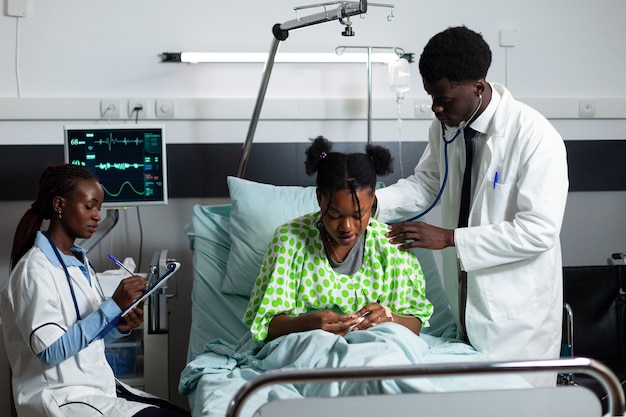 Médico afro-americano consultando jovem paciente na enfermaria do hospital