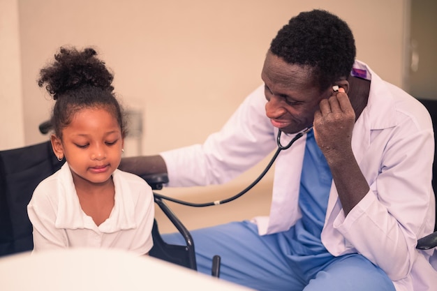Médico afro-americano examinando garoto negro com estetoscópio
