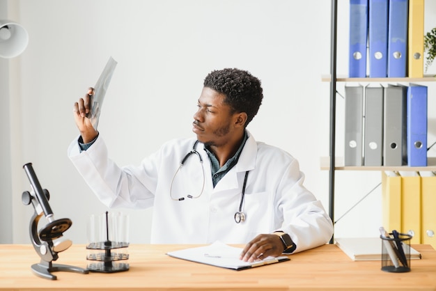 Médico afro-americano examinando o raio-x de um paciente no consultório