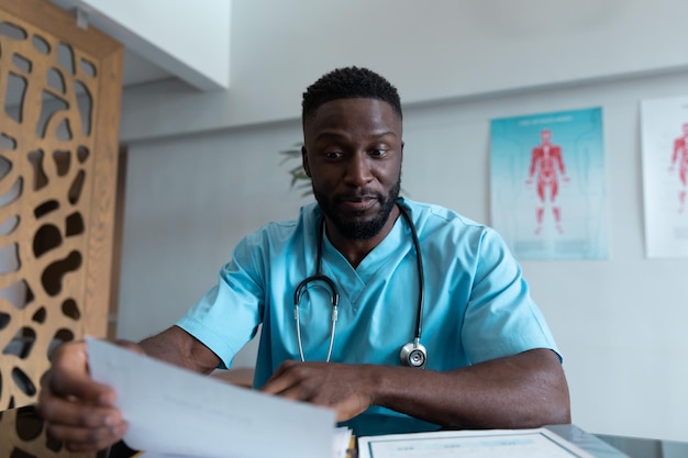 Médico afro-americano na mesa falando e gesticulando durante consulta por videochamada