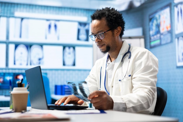 Médico afroamericano analizando los resultados de las pruebas de radiografía para el plan de recuperación
