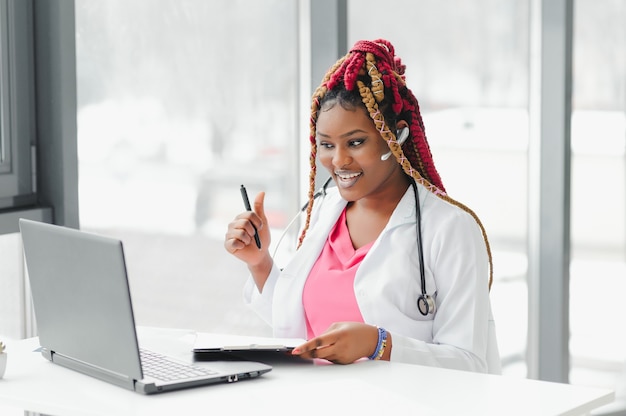 Médico afroamericano en auriculares consultando con el paciente por teléfono