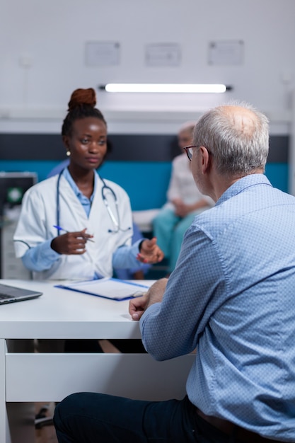 Médico afroamericano discutiendo los resultados del chequeo con el paciente anciano