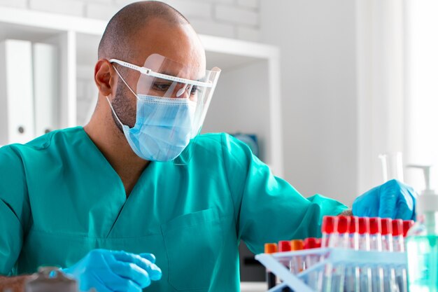 Médico afroamericano o trabajador de laboratorio examina la muestra de sangre en la clínica