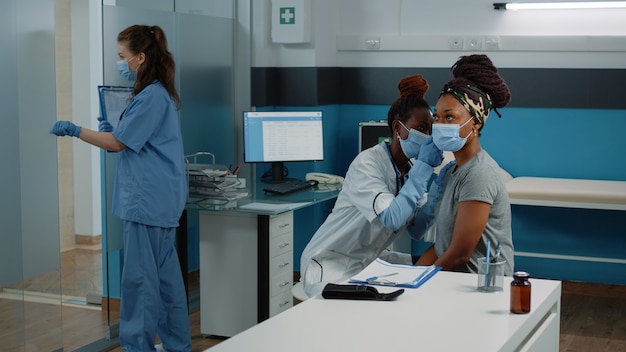 Médico afroamericano con otoscopio para examen de oído