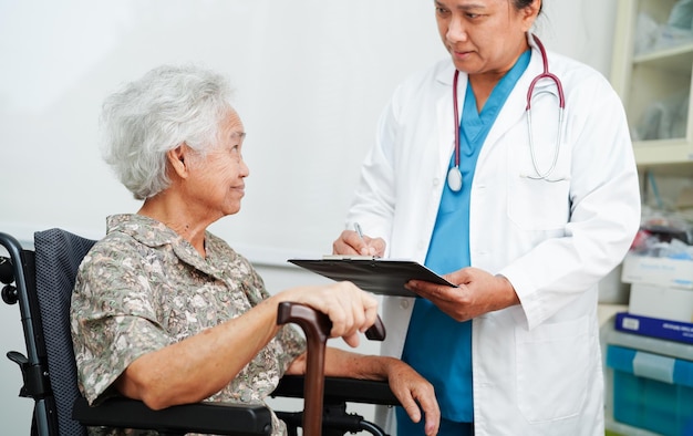 Médico ajuda paciente idosa asiática com deficiência no conceito médico de hospital de enfermagem