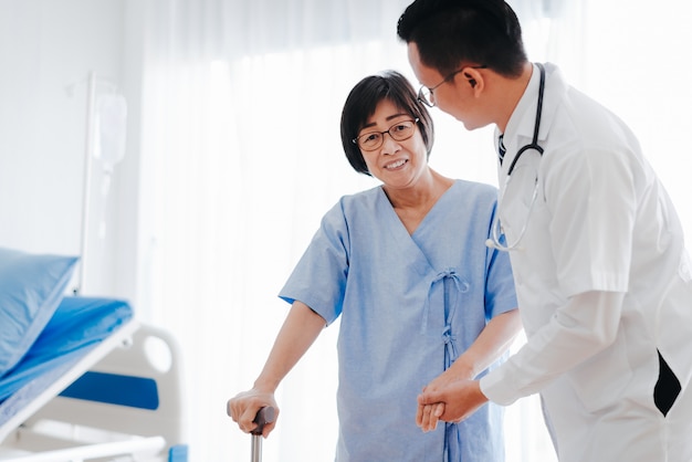 Médico ajudando mulher sênior andando com uma bengala