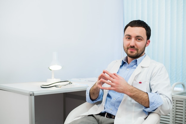 Médico alegre conversando e olhando. Médico em conversa com o paciente enquanto está sentado no hospital.