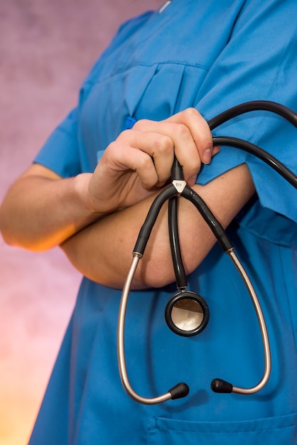 Médico alegre e atraente em uniforme médico posando com estetoscópio e distintivo no hospital