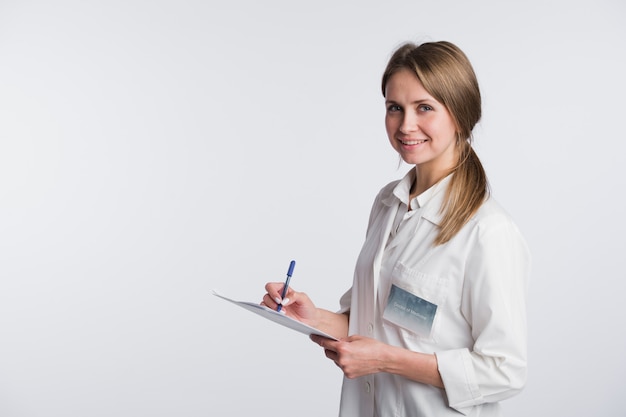 Médico alegre mulher tomando notas. Isolado no branco