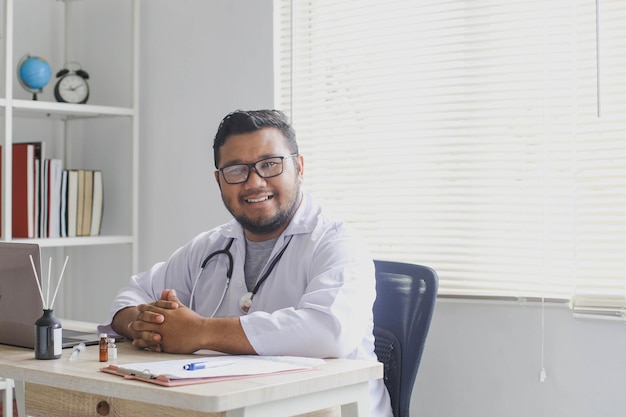 Médico alegre sentado en el consultorio médico