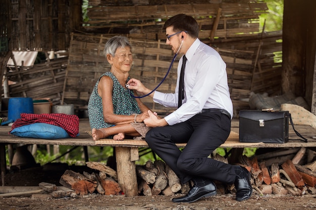 Médico americano examina idosos asiáticos usando um aparelho auditivo.