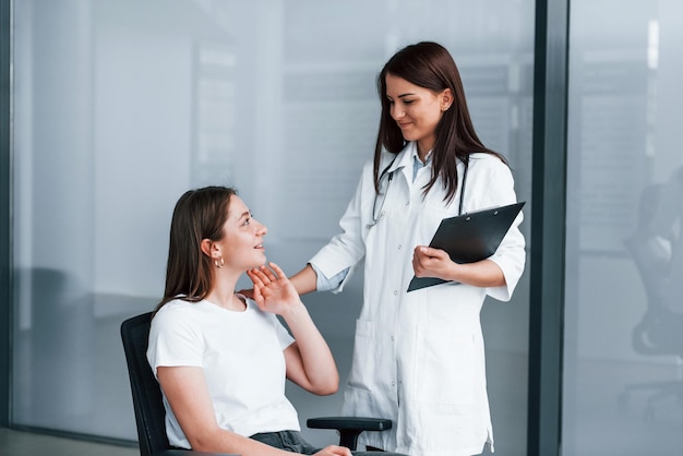 Médico amigável ouvindo o paciente Jovem tem uma visita com médica na clínica moderna