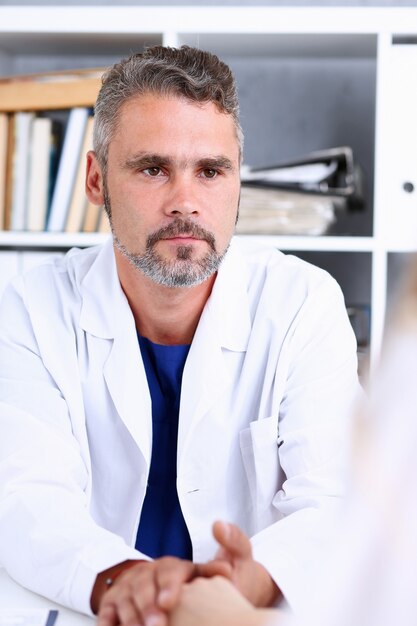 Médico amigável segurando braço feminino no escritório