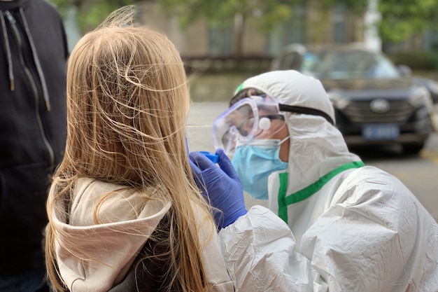 Médico añadiendo una prueba de coronavirus a una niña con un hisopo médico