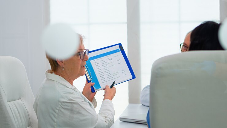 Foto el médico anciano está haciendo una lluvia de ideas para discutir los problemas médicos que apuntan en el portapapeles que presenta la lista de pacientes enfermos. equipo de médicos que trabajan en la oficina del hospital discutiendo los síntomas de la enfermedad