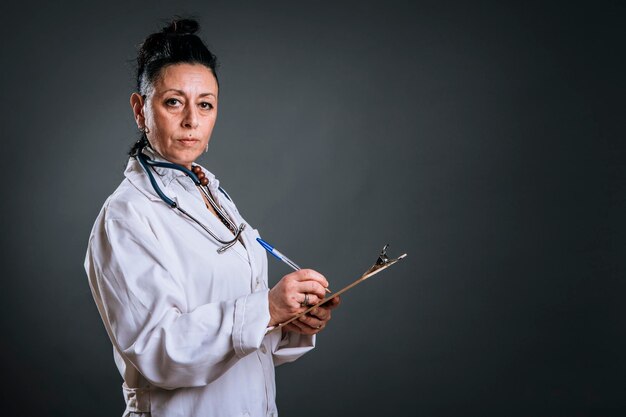 Médico anotando em sua pasta olhando para a câmera na foto do estudo