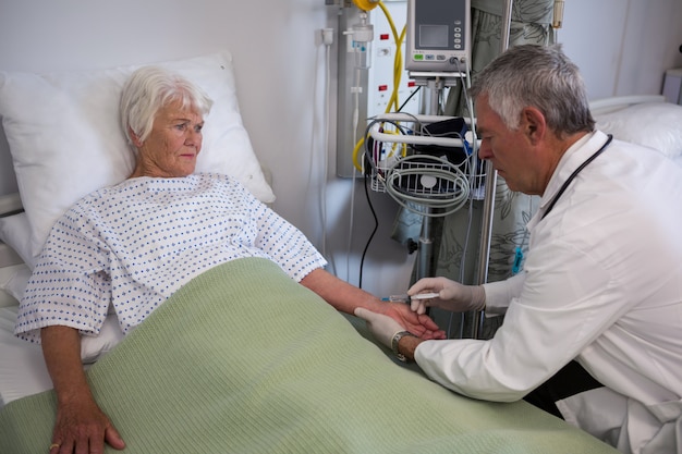 Foto médico aplicando injeção em paciente sênior