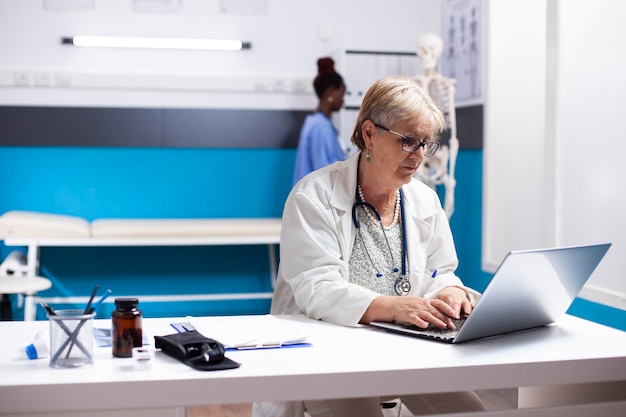 Médico aposentado usando laptop no hospital
