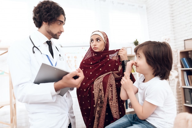 Un médico árabe diagnostica a un niño pequeño.