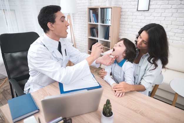 Médico árabe está haciendo una prueba de garganta para el niño.