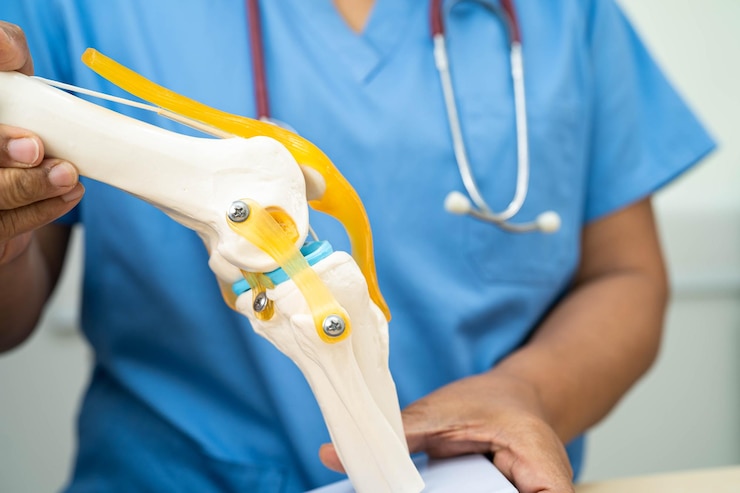 Foto médico asiático apresenta modelo de articulação do joelho para paciente idoso para cirurgia ortopédica