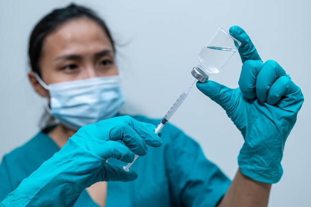 Foto médico asiático com seringa e vacina para proteger o vírus covid19 em fundo branco