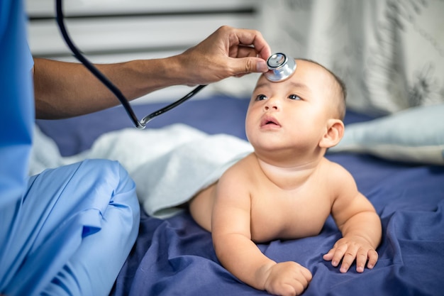 Foto médico asiático examina bebê recém-nascido com estetoscópio no hospital