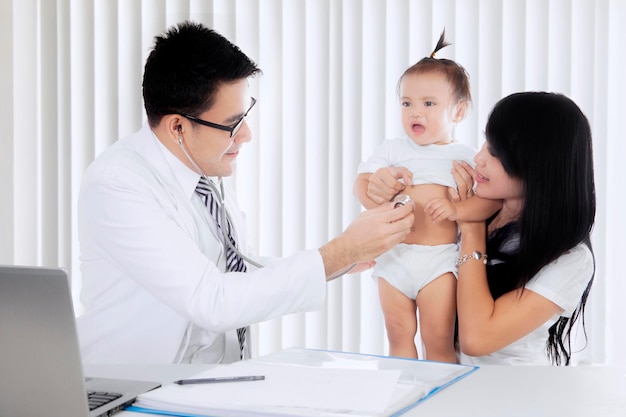 Médico asiático examinando a una niña con un estetoscopio aislado en la clínica