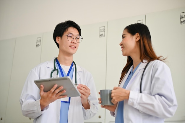 Médico asiático inteligente discutindo seus casos médicos com uma colega durante a pausa para o café