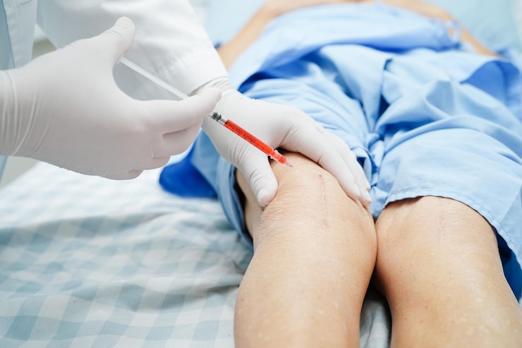 Foto un médico asiático inyecta plasma rico en ácidos hialurónicos y plaquetas en la rodilla de una mujer mayor para que camine sin dolor.