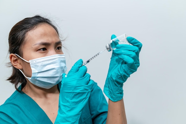 Médico asiático con jeringa y vacuna para proteger el virus covid19 sobre fondo blanco.