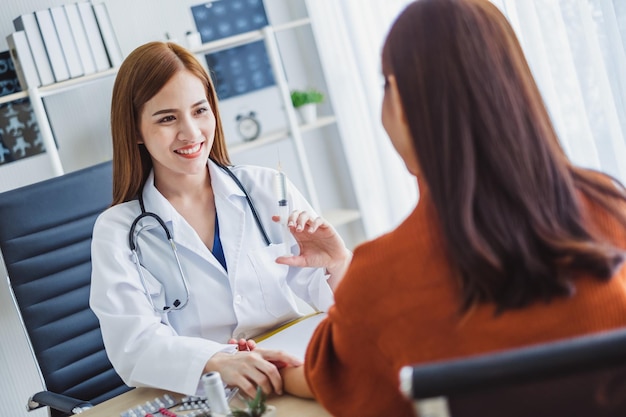 Médico asiático mujer sosteniendo jeringa aguja de inyección con joven paciente asiático mujer concepto médico asiático