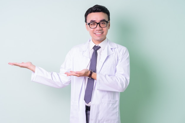 Médico asiático de pie sobre fondo verde