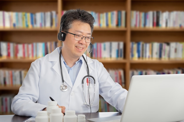 Un médico asiático que consulta remotamente con un paciente. Concepto de telesalud.