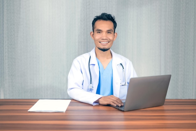 Médico asiático que trabaja con una computadora portátil en el consultorio del hospital Concepto de consultoría y terapia