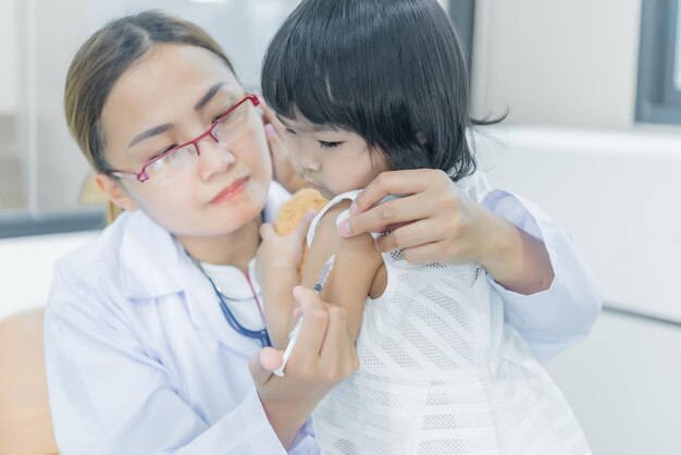 Un médico asiático que usa un estetoscopio para comprobar su respiración y el corazón de una chica encantadora comprueba la salud de los niños de Tailandia