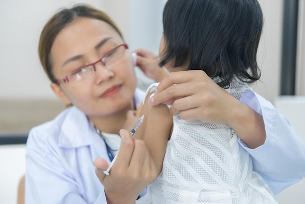 Un médico asiático que usa un estetoscopio para comprobar su respiración y el corazón de una chica encantadora comprueba la salud de los niños de Tailandia