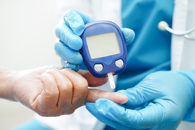 Médico asiático que usa medidor digital de glucosa para verificar el nivel de azúcar en la sangre de la muestra para el tratamiento de la diabetes