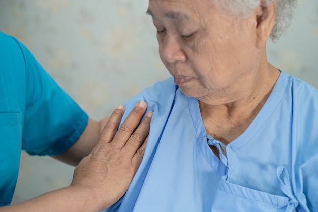 Médico asiático tocar paciente mujer mayor asiática con amor.