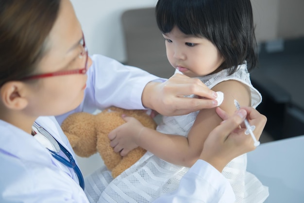 Médico asiático usando um estetoscópio para verificar sua respiração e coração de uma linda garota verificar a saúde das criançasTailândia