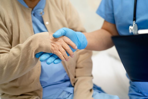 Médico asiático vestindo ppe novo normal para verificar a segurança do paciente proteger infecção covid-19 surto de coronavirus na enfermaria de quarentena do hospital.