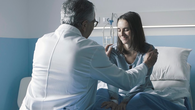 Médico atencioso animando um paciente no hospital