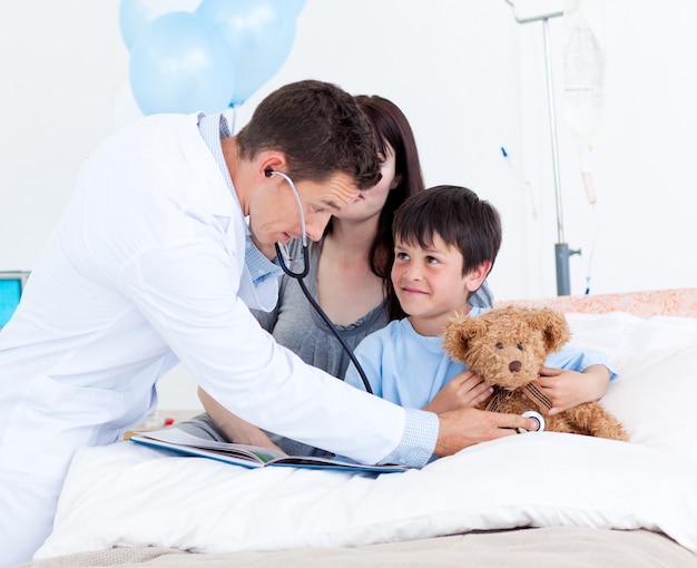 Médico atencioso brincando com um garotinho e sua mãe