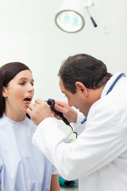 Médico auscultando a boca de seu paciente