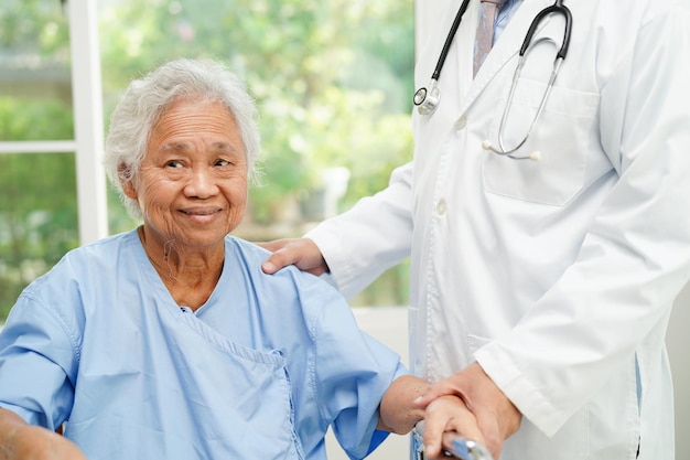 El médico ayuda a una anciana asiática a caminar con un andador en el concepto médico del hospital de enfermería