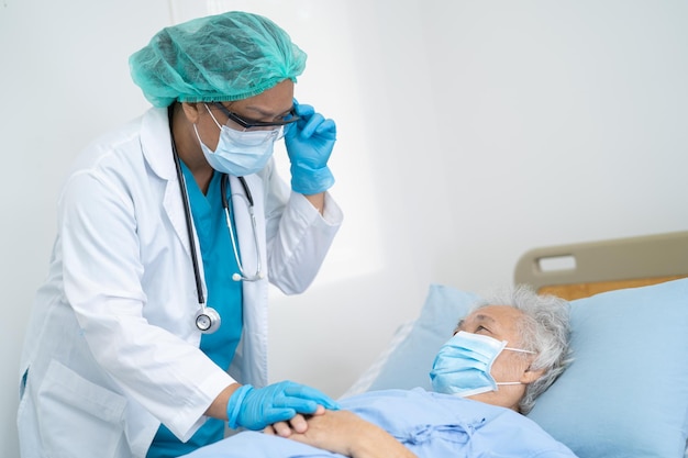 El médico ayuda a una paciente asiática mayor o anciana que usa una máscara facial en el hospital para proteger la infección de seguridad y matar el coronavirus Covid-19.